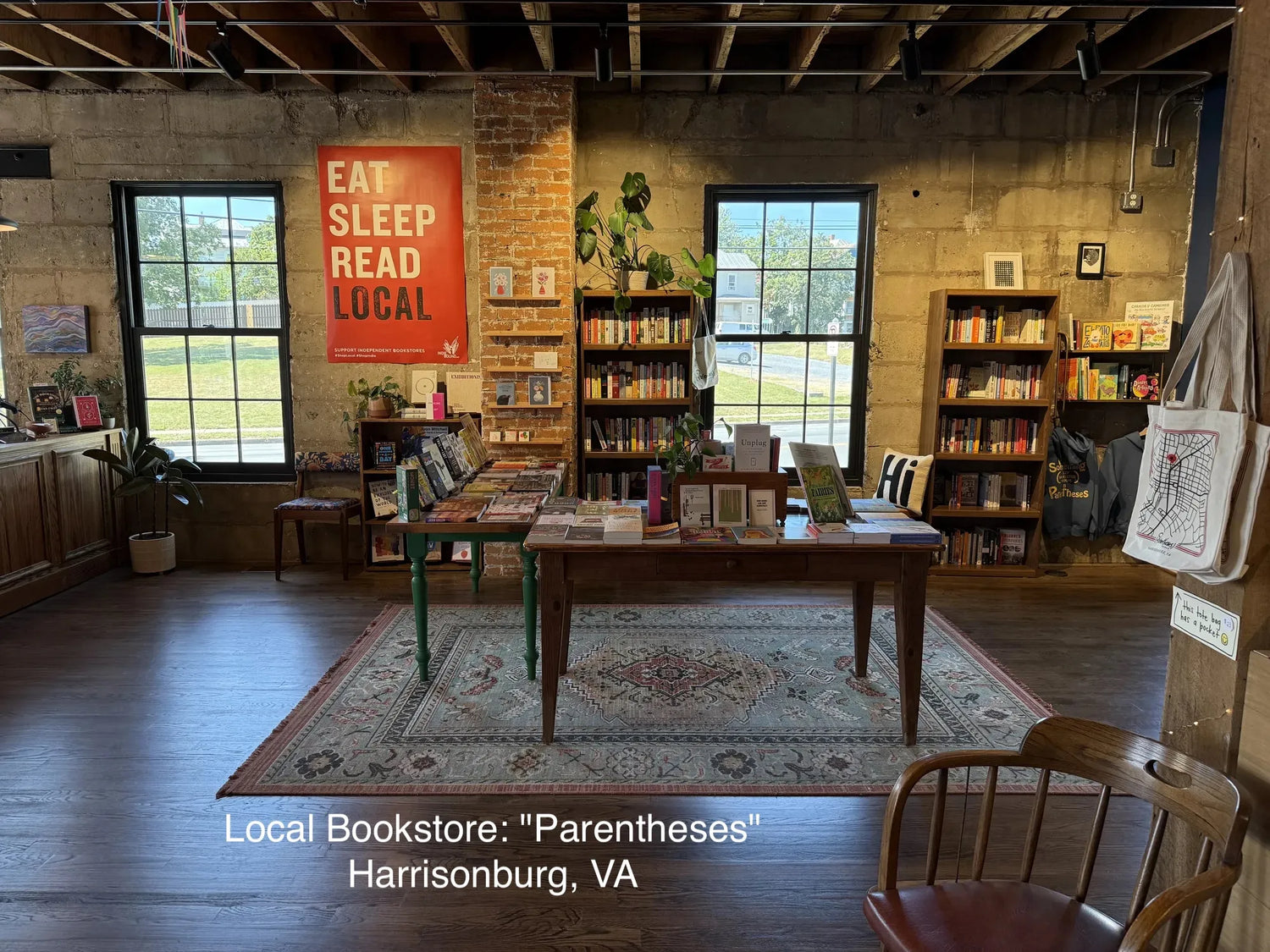Bookstore interior with bookshelves, a table, chairs, and a 'Eat Sleep Read Local' sign.