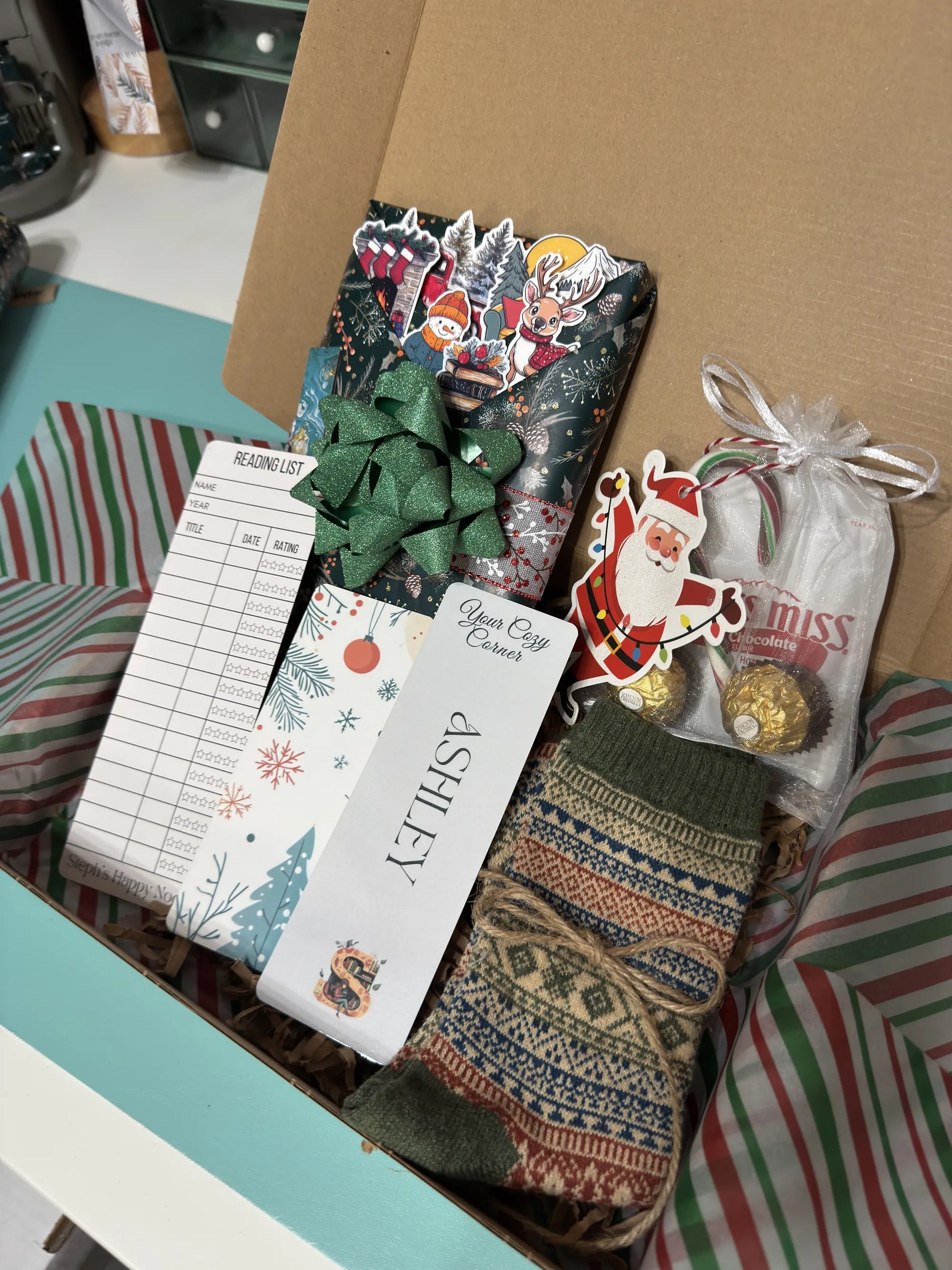 Collection of Christmas-themed items including bookmarks, stickers, Christmas tag, a bow, and a patterned sock in a box.