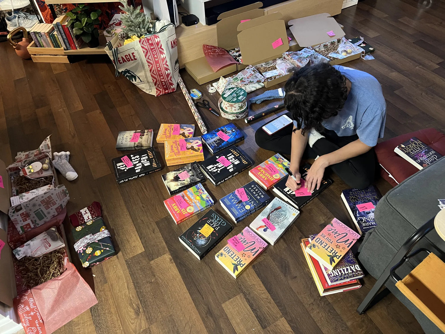 Stephanie organizing books on a wooden floor with boxes and items around